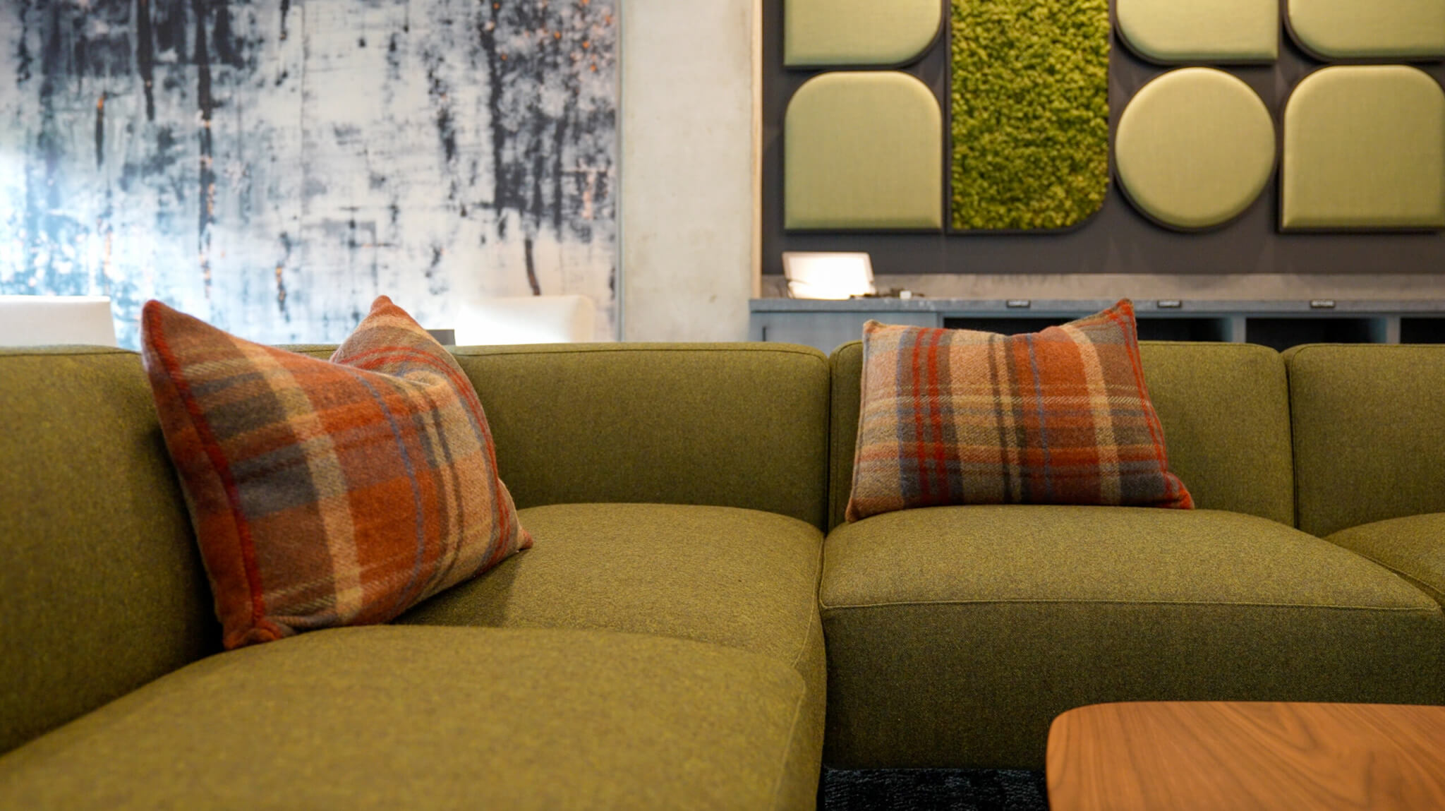 Two plaid wool cushion covers on an olive green lounge sofa in a lobby